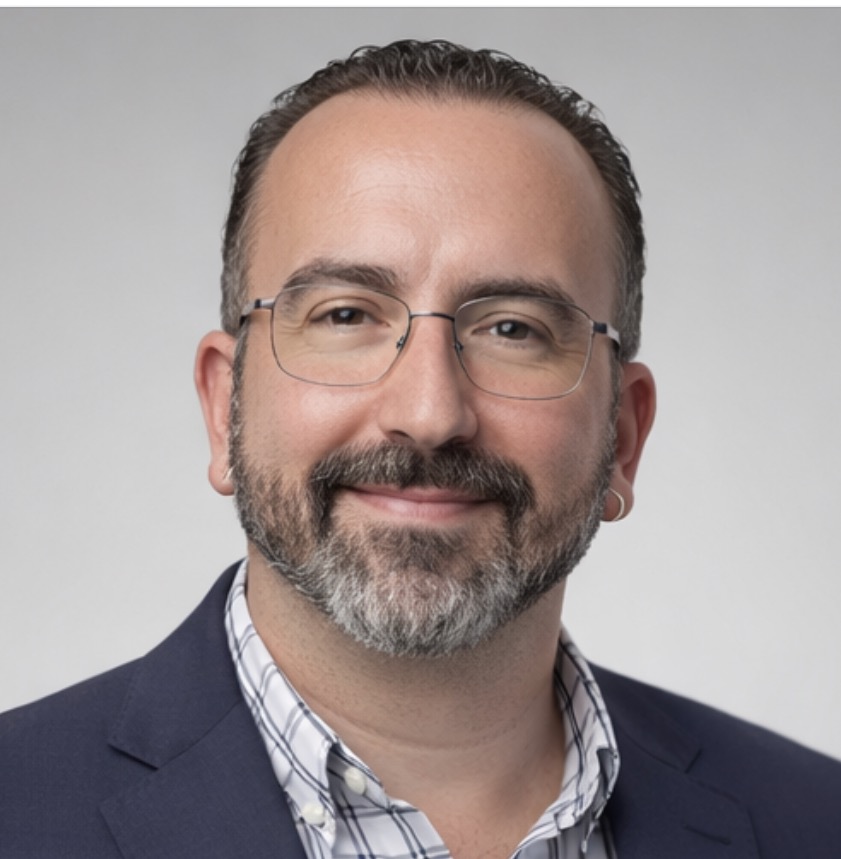 Man with dark hair and light skin wearing glasses and smiling